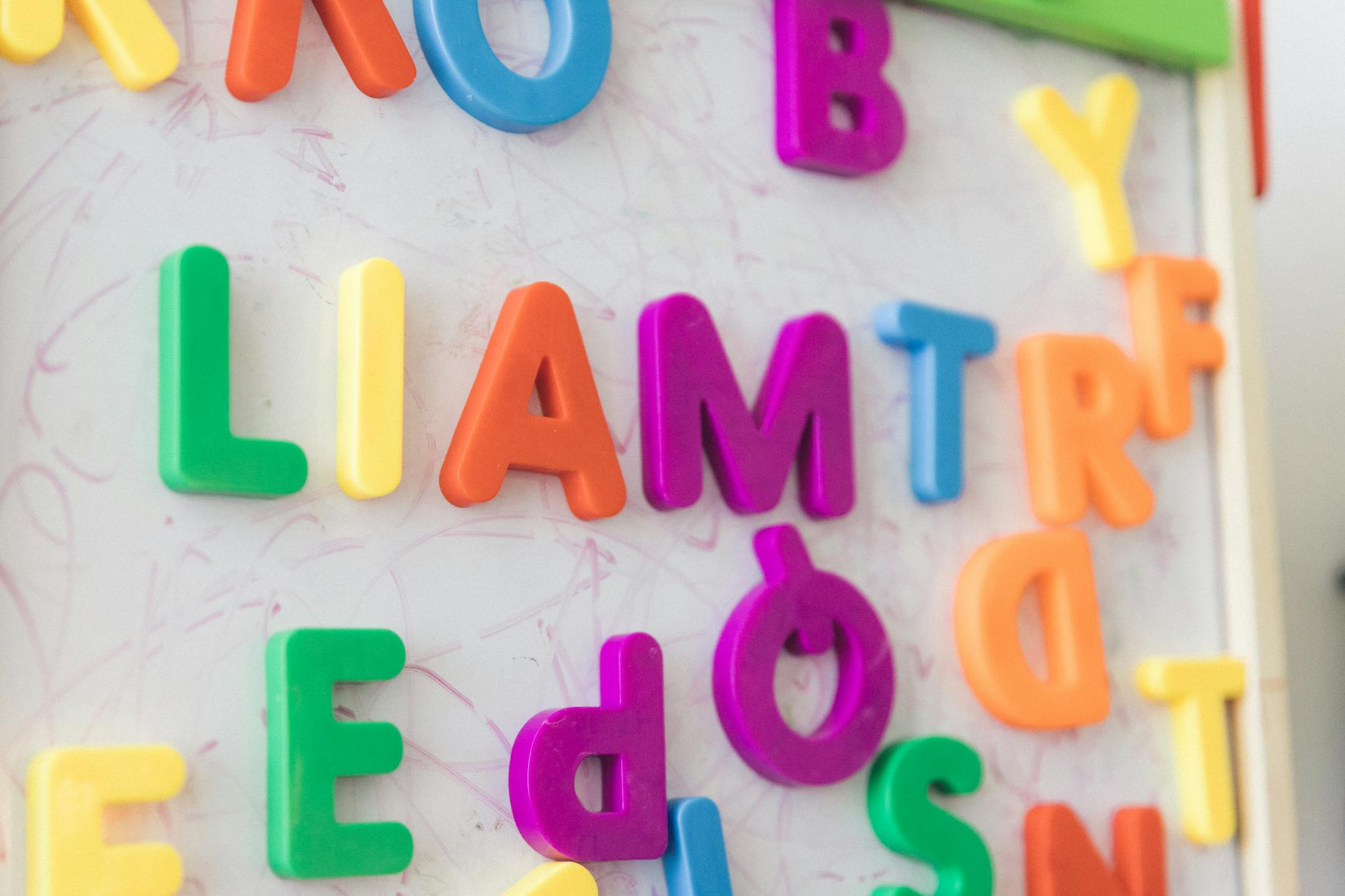 Brightly colored magnetic letters arranged on a whiteboard for education.