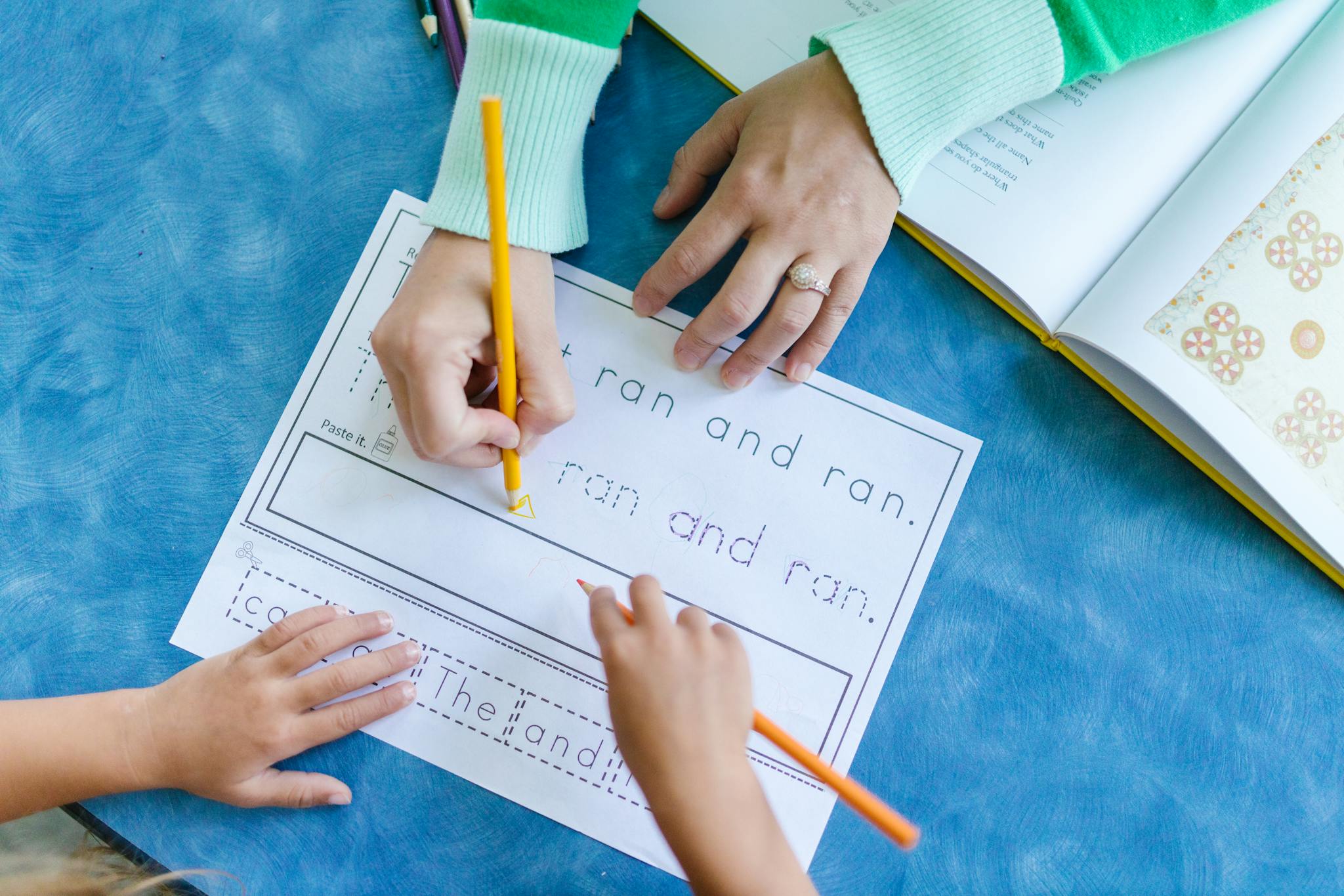 Child tracing letters with teacher guidance in a school setting.